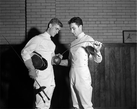 simsearch:846-02792348,k - 1940s TWO MEN WEARING FENCING OUTFITS HOLDING RAPIERS ONE HOLDING FACE MASK UNDER ARM OTHER FLEXING RAPIER AS OTHER WATCHES Stock Photo - Rights-Managed, Code: 846-02797420