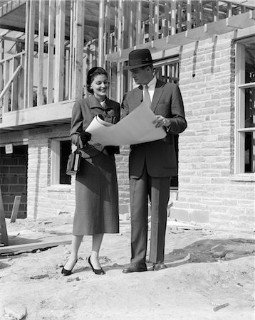1950s COUPLE LOOKING AT BUILDING PLANS STANDING IN FRONT OF UNFINISHED HOUSE Stock Photo - Rights-Managed, Code: 846-02797422