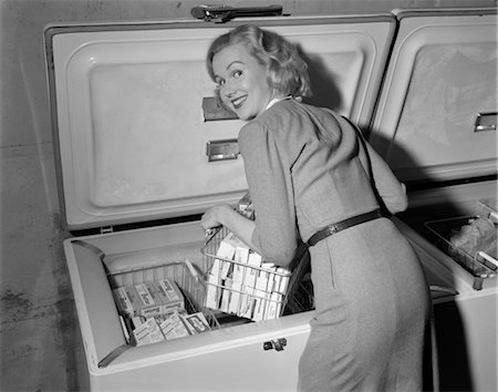 1950s BLOND WOMAN LIFTING WIRE BASKET FOOD ITEMS FROM A DEEP FREEZER LOOKING OVER HER SHOULDER Foto de stock - Con derechos protegidos, Código: 846-02797487