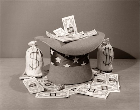1940s STILL LIFE OF UPSIDE-DOWN UNCLE SAM HAT FILLED WITH & SURROUNDED BY LARGE BILLS & MONEY BAGS Stock Photo - Rights-Managed, Code: 846-02797566