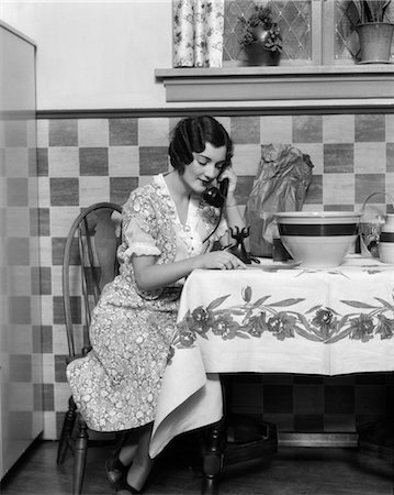 simsearch:846-02793248,k - 1920s WOMAN SITTING AT KITCHEN TABLE WITH TABLE CLOTH WHILE SMILING ON PHONE Stock Photo - Rights-Managed, Code: 846-02797634