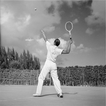 fitness black and white - 1930s BACK VIEW OF MAN PLAYING TENNIS ABOUT TO HIT THE BALL SUMMER OUTDOOR Foto de stock - Con derechos protegidos, Código: 846-02797679