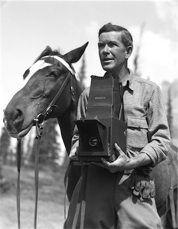 1920s OUTDOOR PHOTOGRAPHER WITH GRAFLEX CAMERA STANDING BESIDE HORSE Foto de stock - Con derechos protegidos, Código: 846-02797723