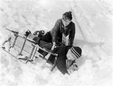 1930s 1940s TWO BOYS LAUGHING IN SNOW JUST FALLEN OFF OF SLED THAT IS TURNED ON ITS SIDE Foto de stock - Direito Controlado, Número: 846-02797741