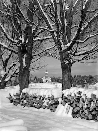 simsearch:846-02792735,k - PILE OF SNOW-COVERED FIREWOOD LOGS BETWEEN TWO TREES WITH COUNTRY CHURCH IN BACKGROUND Stock Photo - Rights-Managed, Code: 846-02797764