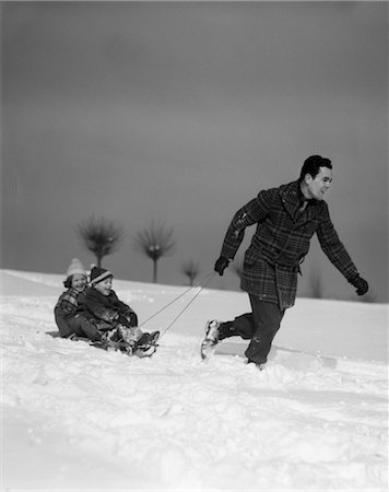1930s FATHER PULLING CHILDREN ON SLED IN SNOW Foto de stock - Direito Controlado, Número: 846-02797804