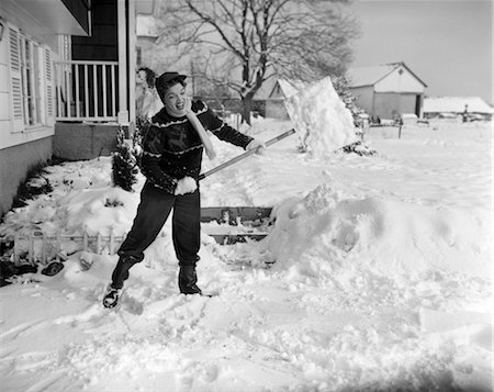 1950s WOMAN STRUGGLE WORKING HARD SHOVEL SNOW FROM SIDEWALK HOUSE WITH PORCH Stock Photo - Rights-Managed, Code: 846-02797817