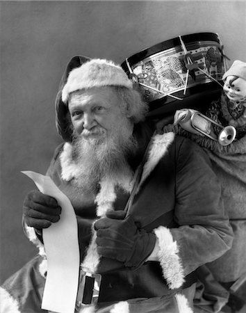 simsearch:846-02795924,k - 1930s SANTA WITH SACK OF TOYS OVER BACK CHECKING HIS LIST Stock Photo - Rights-Managed, Code: 846-02797879