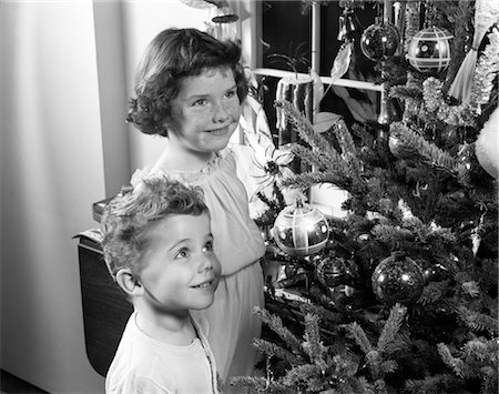 simsearch:846-02794230,k - 1950s BOY GIRL SMILING UP AT CHRISTMAS TREE DECORATIONS ORNAMENTS PINE FIR CANDLE IN WINDOW WISHING DREAMING Foto de stock - Con derechos protegidos, Código: 846-02797882