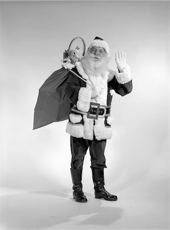 ANNÉES 1960 SOURIANT SANTA AVEC UN SAC DE JOUETS SUR SON DOS AGITANT JOLLY Photographie de stock - Rights-Managed, Code: 846-02797906