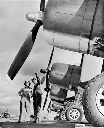 photograph 1940 - 1940s WWII MARINE CORP TECHNICIAN WITH WOMAN RESERVIST INSPECTING FIGHTER AIRCRAFT ON THE AIR FIELD Stock Photo - Rights-Managed, Code: 846-02791733