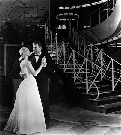 1940s ROMANTIC COUPLE MAN AND WOMAN FORMALLY DRESSED DANCING NEAR ART DECO STAIRCASE Foto de stock - Con derechos protegidos, Código: 846-02791806