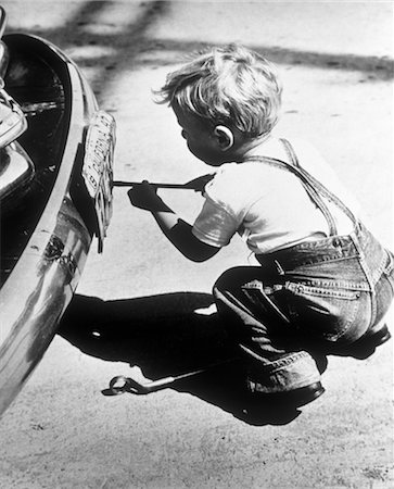 1950s TODDLER BOY PLAYING AT CAR REPAIR REMOVING LICENSE PLATE WITH SCREWDRIVER Stock Photo - Rights-Managed, Code: 846-02791802