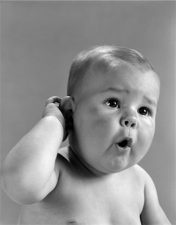 1960s HEAD SHOT OF BABY WITH HAND TO ONE EAR AND MOUTH OPEN INDOOR Stock Photo - Rights-Managed, Code: 846-02791996