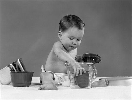 spremiagrumi a mano - 1950s BABY IN DIAPER PLAY WITH KITCHEN UTENSILS PYREX MEASURING CUP JUICER POT PAN CONCENTRATION VINTAGE Fotografie stock - Rights-Managed, Codice: 846-02792108