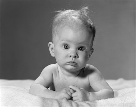 expansion (accroissement de volume) - ANNÉES 1960 PORTRAIT BÉBÉ COUCHÉ SUR VENTRE AVEC DÉSORDRE CHEVEUX ET DES YEUX EXORBITÉS Photographie de stock - Rights-Managed, Code: 846-02792115