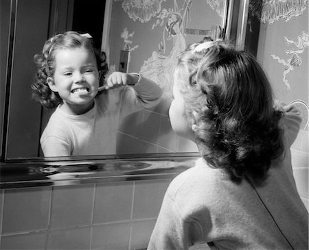 person's - 1950s GIRL LOOKING IN BATHROOM MIRROR BRUSHING TEETH Foto de stock - Con derechos protegidos, Código: 846-02792126