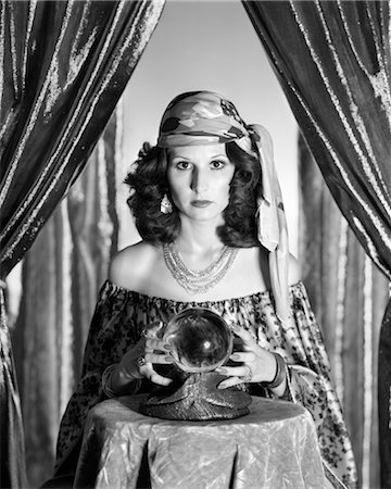1970s GYPSY BETWEEN SPARKLY CURTAINS WITH HANDS AROUND CRYSTAL BALL STARING INTO CAMERA Stock Photo - Rights-Managed, Code: 846-02792209