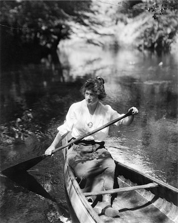 1920s WOMAN WITH UPSWEPT HAIR PADDLING WOODEN CANOE IN STREAM Stock Photo - Rights-Managed, Code: 846-02792239