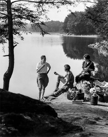 1920s 1930s 3 PEOPLE PICNICKING BY LAKE MAN WEARING JODHPURS STANDING TWO SEATED WOMEN BERKSHIRES MA ONATA LAKE Stock Photo - Rights-Managed, Code: 846-02792259