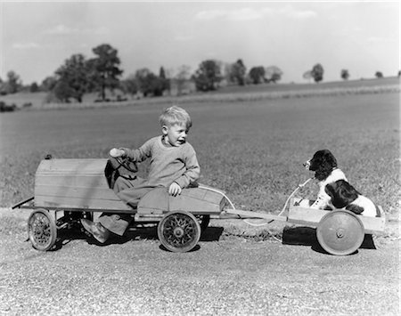 1930s 1940s BOY IN WOODEN TOY CAR PULLING DOG BEHIND IN WAGON Foto de stock - Con derechos protegidos, Código: 846-02792399