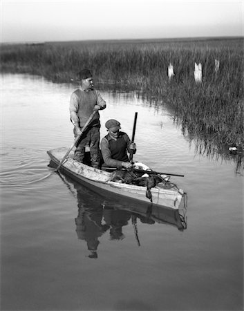 1920s TWO MEN DUCK HUNTERS WITH SHOTGUNS IN A SKIFF WILLIS WHARF VIRGINIA Stock Photo - Rights-Managed, Code: 846-02792410