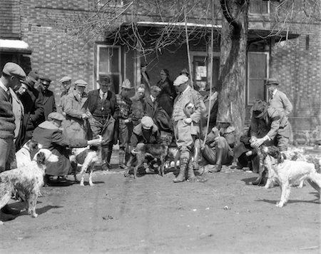 simsearch:846-02792336,k - 1920s 1930s HUNTING DOGS WITH TRAINERS ASSEMBLED FOR FIELD TRIALS IN FRONT OF BRICK BUILDING Fotografie stock - Rights-Managed, Codice: 846-02792462