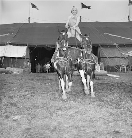 1950ER JAHRE WEIBLICH ZIRKUSKÜNSTLER REITEN RITTLINGS AUF ZWEI PFERDE VOR ZELT STEHEND Stockbilder - Lizenzpflichtiges, Bildnummer: 846-02792475