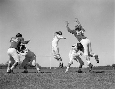 quarterback - 1960s FIVE MEN PLAYING FOOTBALL TWO PLAYERS BLOCKING OPPONENTS WHILE QUARTERBACK THROWS BALL Fotografie stock - Rights-Managed, Codice: 846-02792718