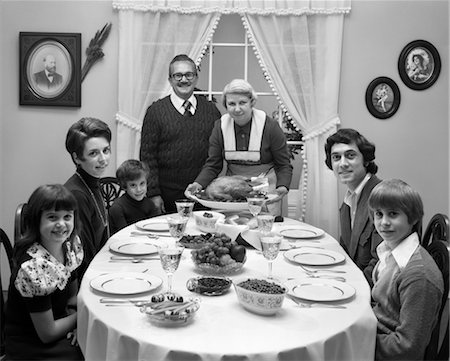 1970s 3 GENERATION FAMILY SITTING DINING ROOM TABLE GRANDMOTHER SETTING DOWN TURKEY PLATTER Stock Photo - Rights-Managed, Code: 846-02792789