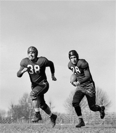 1940s 1950s FOOTBALL PLAYER RUNNING WITH BALL AS DEFENSE TEAM MEMBER RUN AHEAD Stock Photo - Rights-Managed, Code: 846-02792839