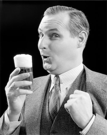 simsearch:846-02794249,k - 1930s MAN HOLDING FULL FOAMY GLASS OF BEER MAKING A FUNNY FACE WITH HIS THUMB HOOKED CONFIDENTLY UNDER HIS VEST LOOKING AT CAMERA Stock Photo - Rights-Managed, Code: 846-02792862