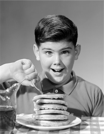 spesso - 1960s SMILING PORTRAIT BOY SITTING EAGERLY BEHIND THICK STACK OF PANCAKES POKING FORK INTO TOP OF STACK Fotografie stock - Rights-Managed, Codice: 846-02792890