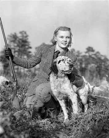 1940ER JAHRE FRAU HÄLT GEWEHR IN EINE HAND PETTING HUND MIT ANDEREN KNIEND IN GRAS TRAGEN TWEED ANZUG Stockbilder - Lizenzpflichtiges, Bildnummer: 846-02792945