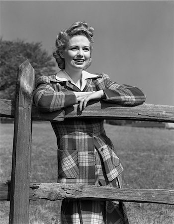 1940s BLOND WOMAN SMILING PORTRAIT LEANING ARMS ON WOODEN FENCE WEARING PLAID TARTAN SUIT FASHION Foto de stock - Con derechos protegidos, Código: 846-02792963