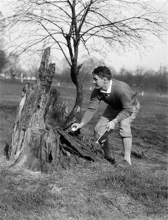 BALLE DE GOLF HOMME GOLFEUR PRENANT DES ANNÉES 1930 SUR GRILLÉE DE SOUCHE D'ARBRE TRONC RÈGLES FAIR PLAY GOLF Photographie de stock - Rights-Managed, Code: 846-02792970