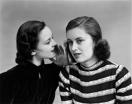 fofoca - 1930s 1940s TWO WOMEN GOSSIPING ONE WHISPERING INTO THE EAR OF THE OTHER WOMAN Foto de stock - Direito Controlado, Número: 846-02792973