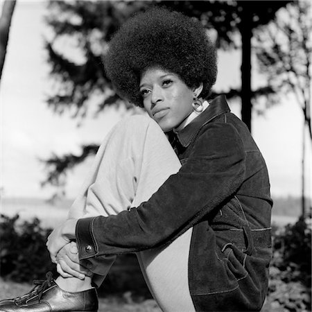 ANNÉES 1970 PORTRAIT FEMME AFRO-AMÉRICAINE ASSIS JAMBES À LA POITRINE AVEC JOUE REPOSANT SUR LE GENOU À LA RECHERCHE HORS TENSION À DISTANCE Photographie de stock - Rights-Managed, Code: 846-02793117