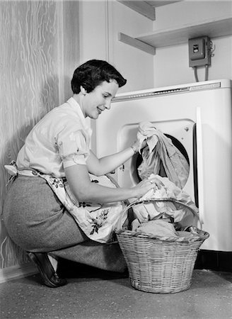 1950s WOMAN KNEELING REMOVING CLOTHES LAUNDRY FROM AUTOMATIC DRYER Foto de stock - Con derechos protegidos, Código: 846-02793134