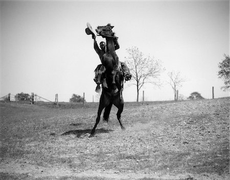 rodeo - 1920s 1930s COWBOY ON HORSE REARING UP MAN WAVING HAT IN HAND Fotografie stock - Rights-Managed, Codice: 846-02793130