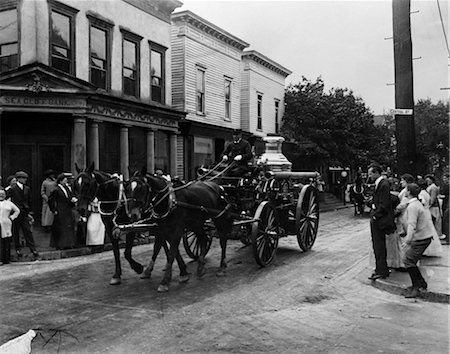 TURN OF THE CENTURY HORSE-DRAWN FIRE TRUCK PARADING THROUGH TOWN WITH PEOPLE LINING STREETS Stock Photo - Rights-Managed, Code: 846-02793149