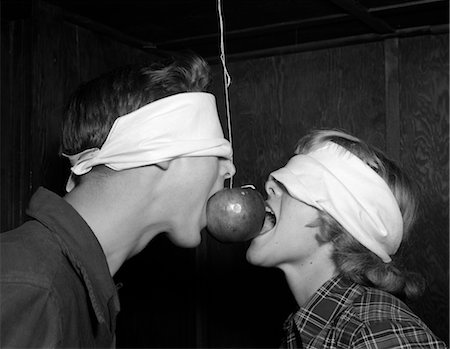 1950s BLINDFOLDED TEENAGE COUPLE BOY GIRL TRYING TO EAT AN APPLE HANGING ON A STRING Stock Photo - Rights-Managed, Code: 846-02793168