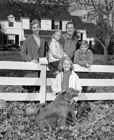 five animals - 1960s FAMILY PORTRAIT FATHER MOTHER TWO DAUGHTERS SON AND DOG GATHERED AROUND WHITE FRONT YARD FENCE LOOKING AT CAMERA Foto de stock - Con derechos protegidos, Código: 846-02793207