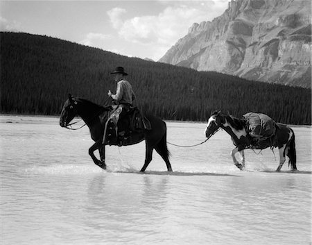 express - 1940s COWBOY ON HORSEBACK CROSSING RIVER WITH 2ND HORSE IN TOW Stock Photo - Rights-Managed, Code: 846-02793221