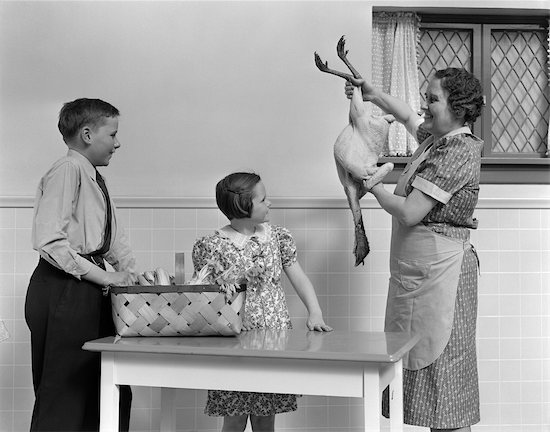 1940s HOUSEWIFE SHOWING RAW FRESH PLUCKED TURKEY TO SON AND DAUGHTER IN KITCHEN Stock Photo - Premium Rights-Managed, Artist: ClassicStock, Image code: 846-02793265