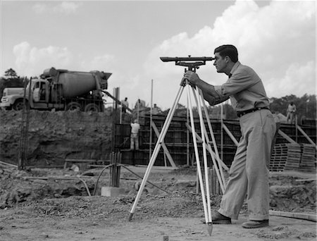 VUE LATÉRALE DES ANNÉES 1960 D'UN TRAVAILLEUR ARPENTAGE CHANTIER AVEC MÉLANGEUR DE CIMENT EN ARRIÈRE-PLAN Photographie de stock - Rights-Managed, Code: 846-02793399