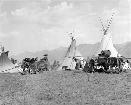 1920s 1930s NATIVE AMERICAN INDIAN CAMP VILLAGE TIPI TEEPEE WAGONS MOUNTAINS IN BACKGROUND KOOTENAI INDIANS BRITISH COLUMBIA Stock Photo - Rights-Managed, Code: 846-02793431