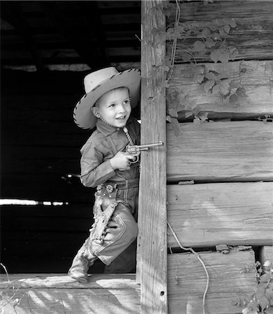 1940s 1950s BOY IN WESTERN OUTFIT WITH COWBOY HAT BLUE JEANS BOOTS CAP GUN AND HOLSTER PLAYING OUTDOORS Stock Photo - Rights-Managed, Code: 846-02793550