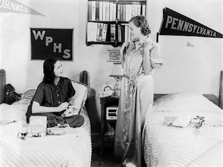 1940s 1930s TWO TEEN GIRLS IN COLLEGE DORM ROOM OPENING PRESENTS PENNANTS ON WALL DORMITORY TWIN BEDS Stock Photo - Rights-Managed, Code: 846-02793567