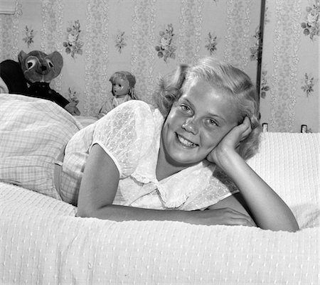 1950s YOUNG BLOND TEEN LYING ON BED SMILING HEAD RESTING ON HAND STUFFED ANIMAL TOYS WALLPAPER Stock Photo - Rights-Managed, Code: 846-02793682